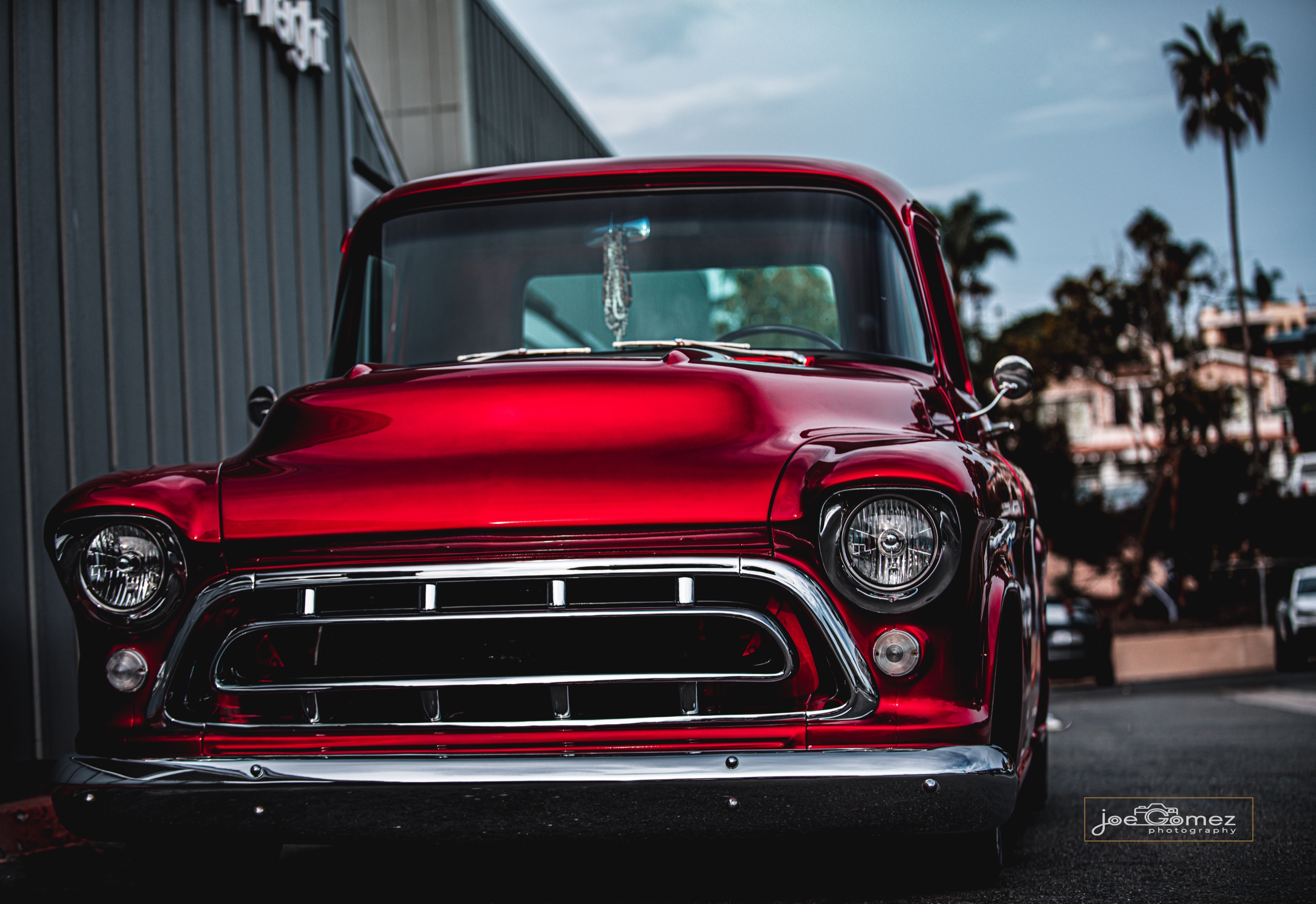 Front-facing portrait of a red classic pickup with chrome grille