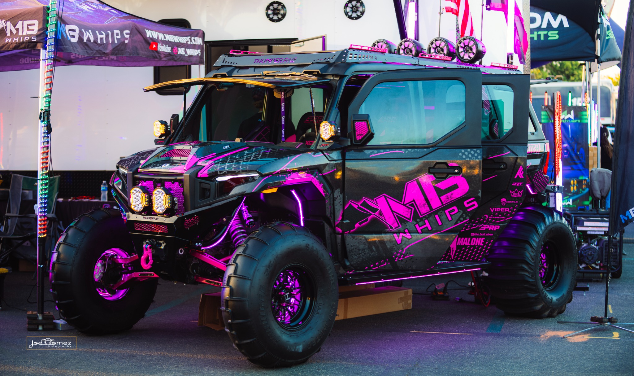 Magenta lighting and bright accents surrounding a vehicle at the MB Whips display