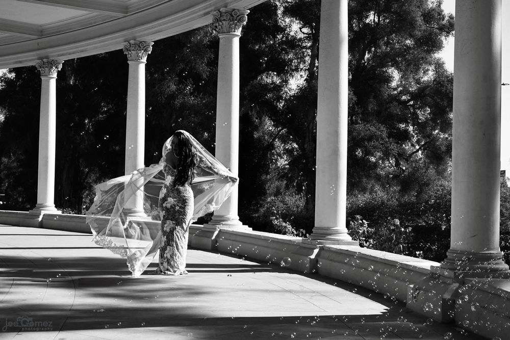 Black-and-white editorial bridal portrait beneath classical columns, created by Joe Gomez for Southern California wedding clients.