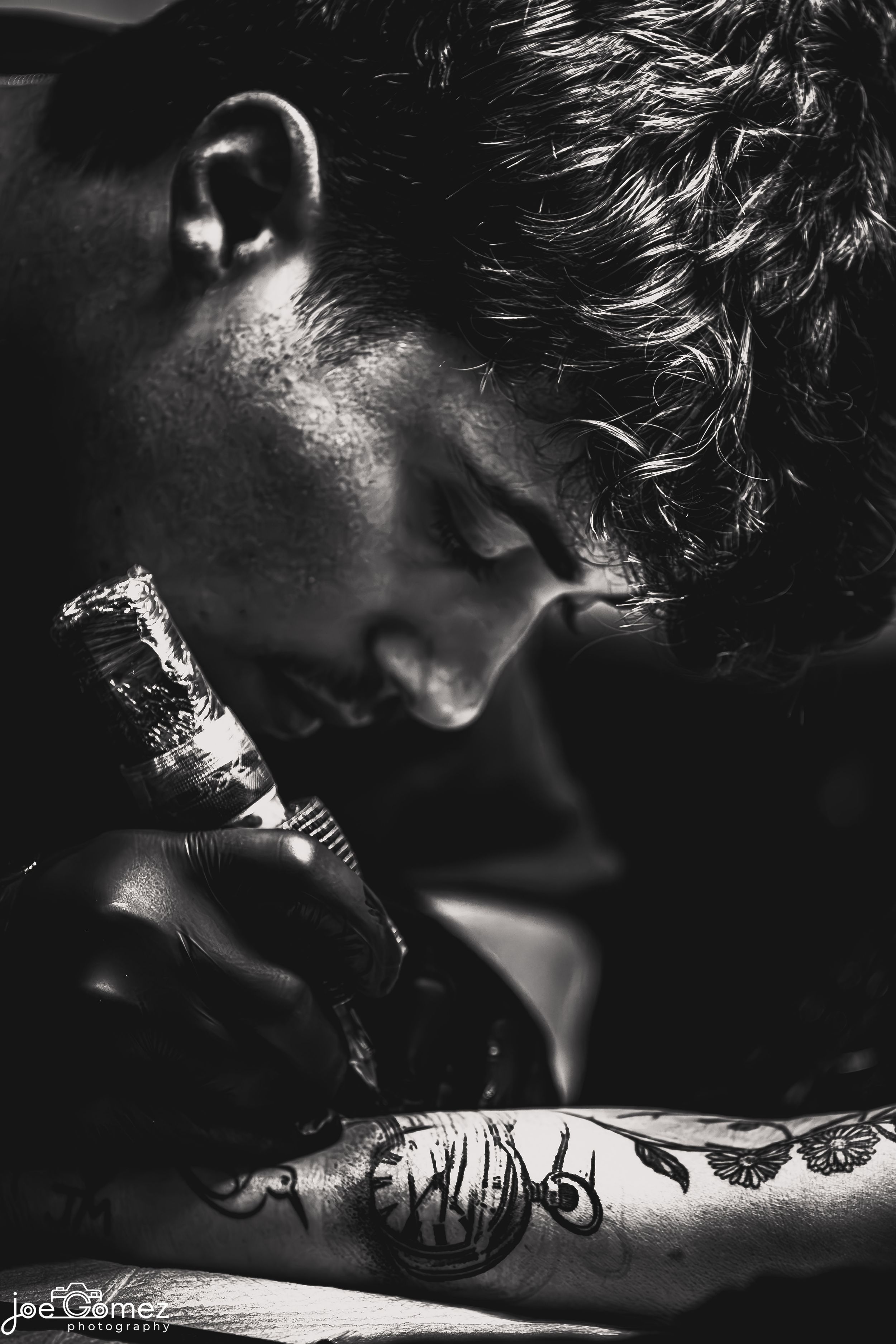 Black-and-white documentary portrait of a tattoo artist at work at Ganga Tattoo in Los Angeles, photographed by Joe Gomez.