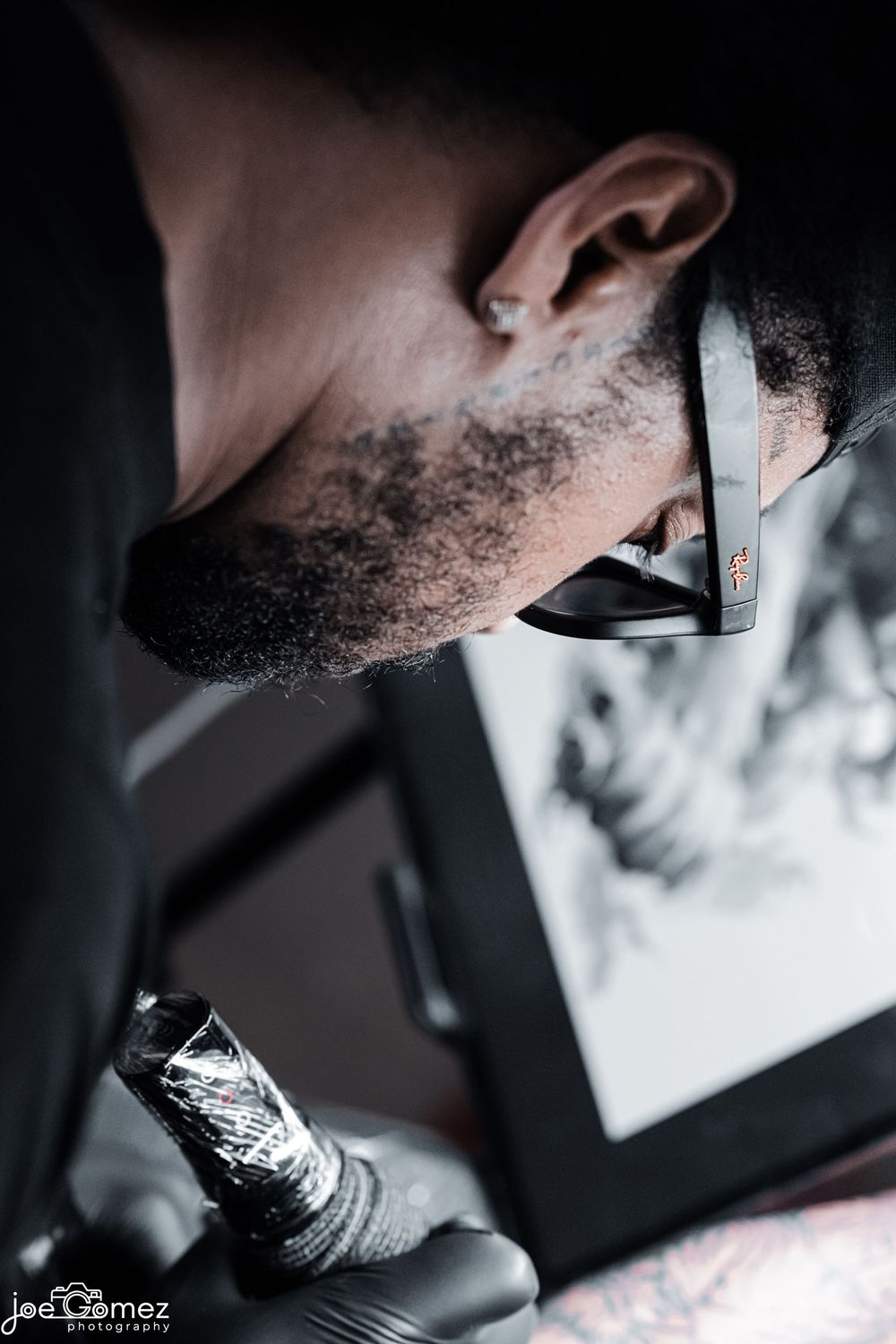 Black-and-white behind-the-scenes portrait of a tattoo artist concentrating on his work in Los Angeles.